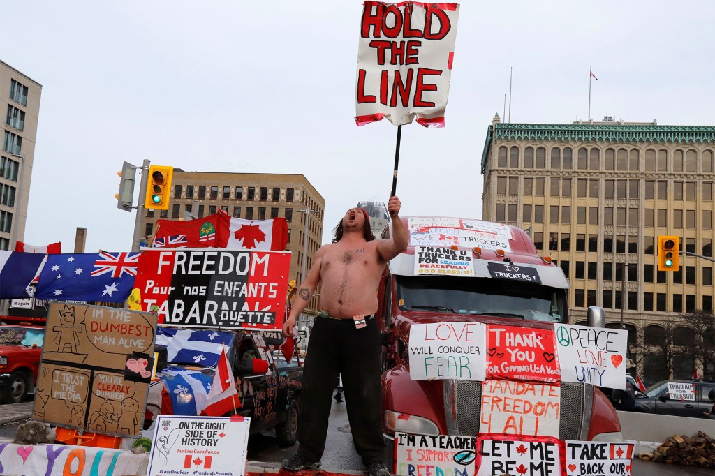 Una persona sostiene un cartel frente a los camiones que bloquean una calle del centro mientras los camioneros y sus seguidores continúan protestando contra los mandatos de una vacuna contra el coronavirus (COVID-19) en Ottawa, Ontario, Canadá.